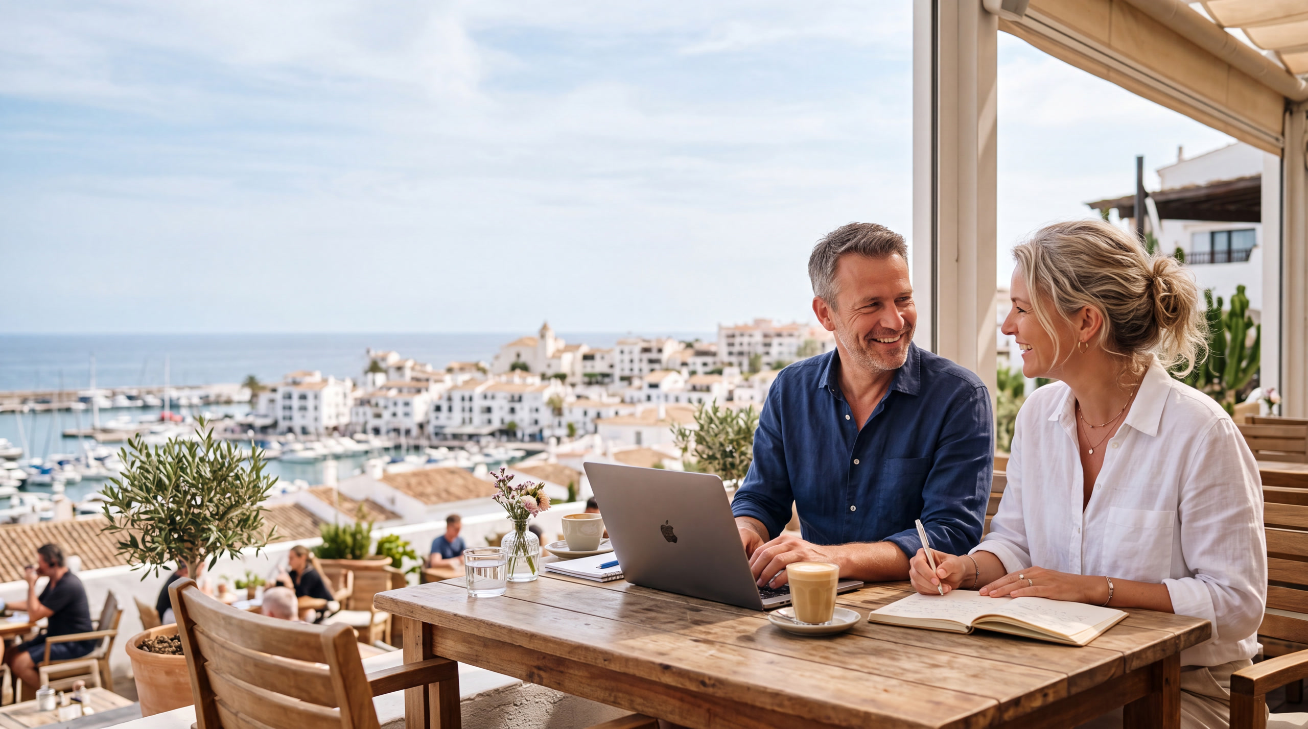 Nederlands ZZP-stel werkt met laptop op een Spaans haventerras met zeezicht